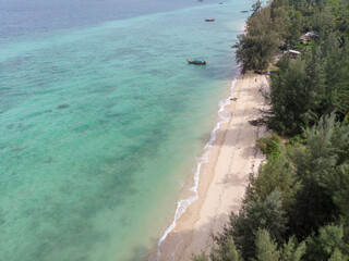 A serene beach with clear turquoise waters and lush greenery.