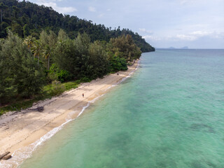Serene tropical beach with clear turquoise waters and lush greenery.