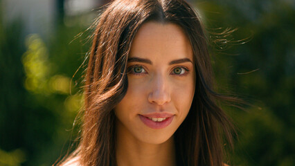 Naklejka premium Close-up smiling happy attractive hispanic woman looking at camera stand in city park street summer sunny day beautiful successful confident arabian girl businesswoman posing outdoors female portrait