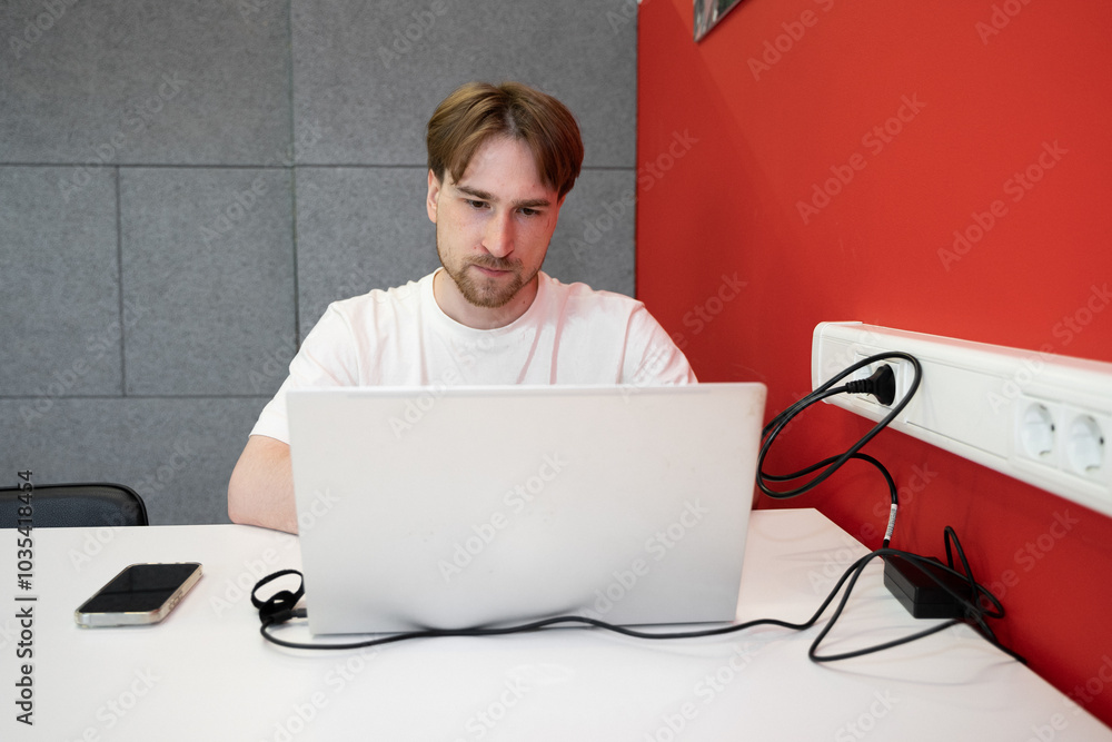 Aufkleber an it specialist programmer diligently types on his laptop in a coworking environment. a smartphone 