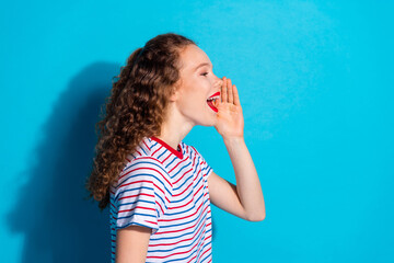 Joyful young woman shouting with excitement against a vibrant blue background