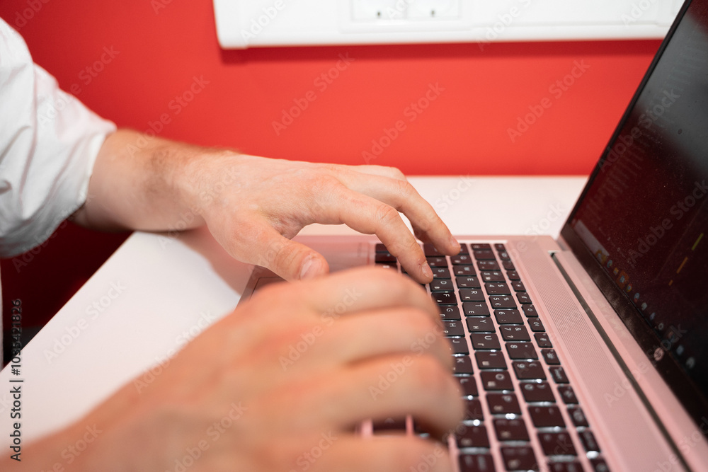 Poster an it specialist is focused on coding at a coworking space, typing on a laptop with a vibrant red wa
