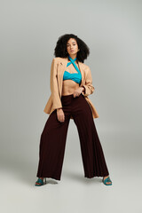 The fashionable woman poses boldly, exuding confidence in her chic ensemble.