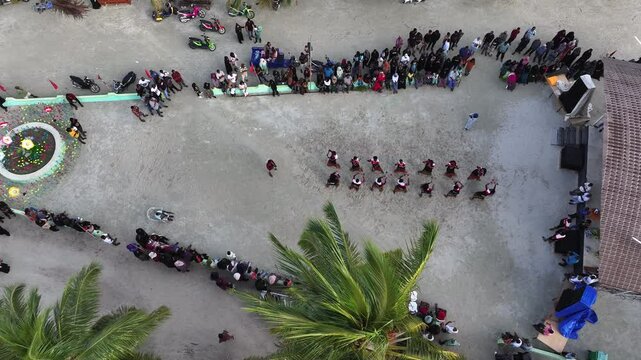 Aerial view of vibrant Eid al Adha celebration with people dancing in parallel rows on a local island, Vashafaru, Maldives.