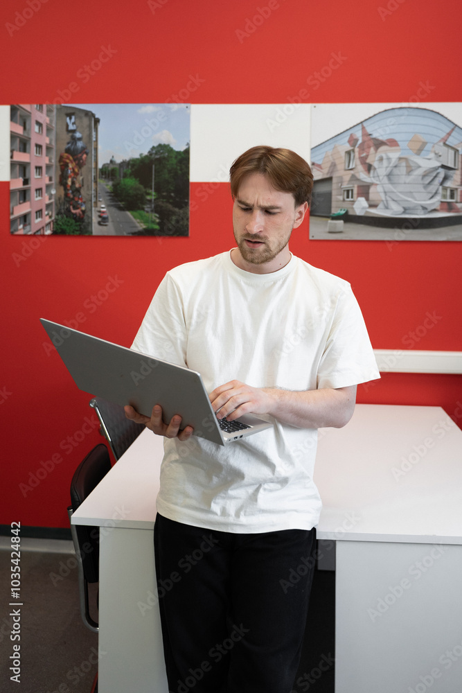 Aufkleber a focused it specialist is programming on a laptop while standing in a stylish coworking environment