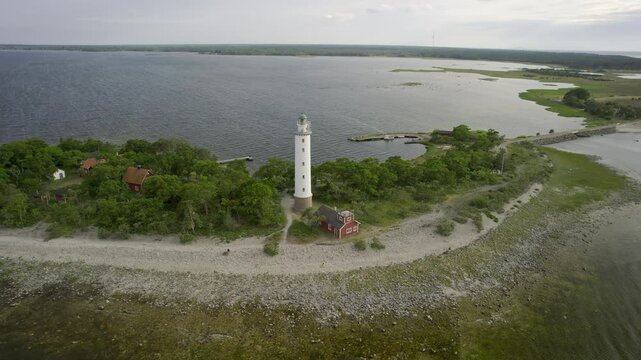 Aerial view of the serene Lange Erik lighthouse surrounded by a tranquil coastal landscape and green forest, Oland Island, Sweden.