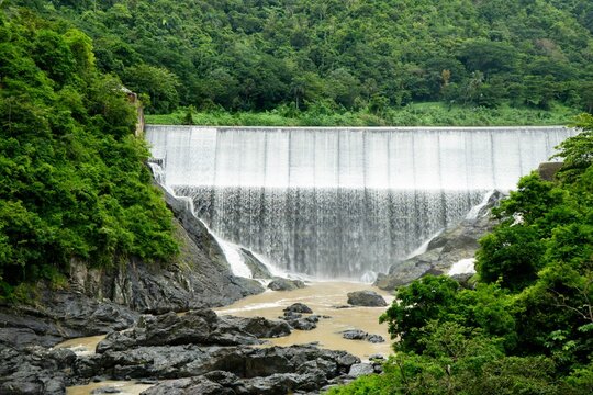 Scenic view of a dam with flowing water, surrounded by lush green trees. Comerio, Puerto Rico