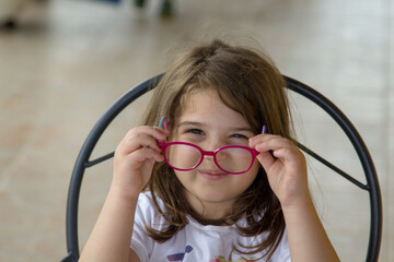 Image of an adorable little girl trying on glasses for the first time
