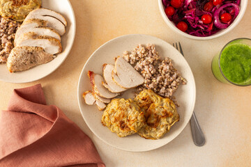Green buckwheat, chicken breast, and zucchini pancakes served with fresh and fermented vegetable salads for a nutritious breakfast or lunch and celery cucumber smoothie
