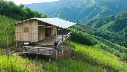 A woman sitting in wooden cabin, playing with cat and looking at a mountain view