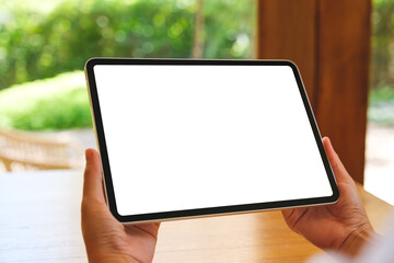 Mockup image of a woman holding digital tablet with blank desktop screen at home