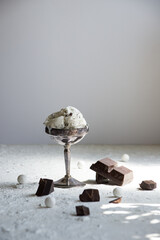 Vintage metal bowl filled with creamy stracciatella ice cream, garnished with chocolate pieces, set...