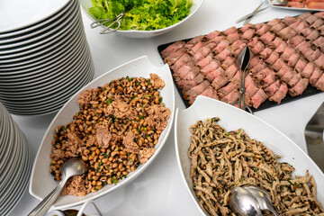Succulent roast beef, flavorful broad beans with tuna, and coriander-infused slices of pork beautifully arranged on a hotel buffet, inviting a delicious dining experience.