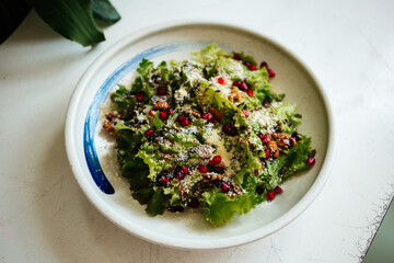 Mix of lettuce leaves with cheese on a round plate on a white table side view