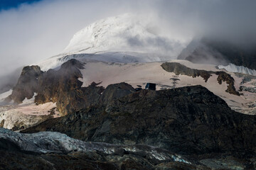 View of majestic snowy mountains and glaciers under dramatic clouds, Saas Valley, Valais, Switzerland.