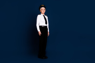 Full size photo of pretty retired female professional airline pilot serious wear aviator uniform isolated on dark blue color background