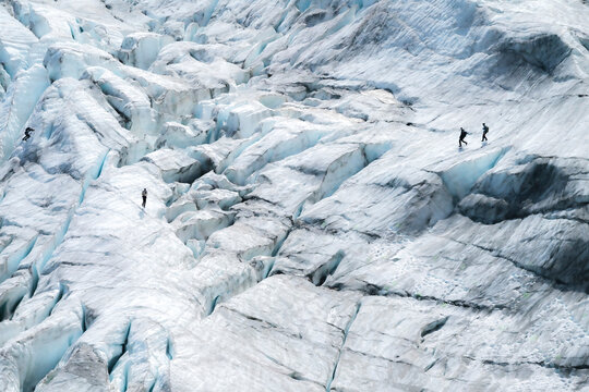 View of majestic Fee Glacier in Saas Valley with four persons hiking in winter, Saas Fee, Switzerland.