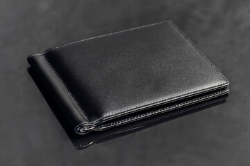Black leather men's wallet for storing money and cards. On a dark background.