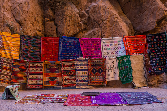 View of colorful traditional rugs in a vibrant artisan market near Todra Gorge, Tinghir, Morocco.