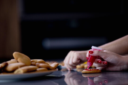 Cute boy decorating gingerbread cookies at home kitchen