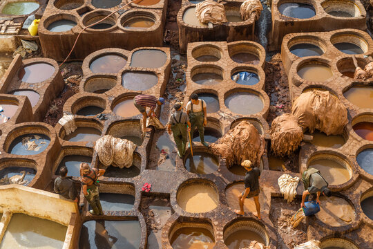 Fès, Morocco - 21 November 2023: View of traditional leather tannery with colorful dye pits and workers, Fes, Morocco.