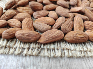 Natural brown fresh almonds on woven jute fabric