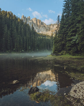 View of tranquil Lago di Mezzo surrounded by majestic mountains and lush forests, Nova Levante, Italy.