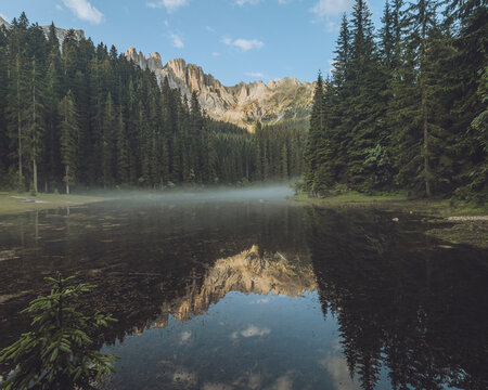 View of tranquil Lago di Mezzo surrounded by majestic mountains and serene forests, Nova Levante, Italy.