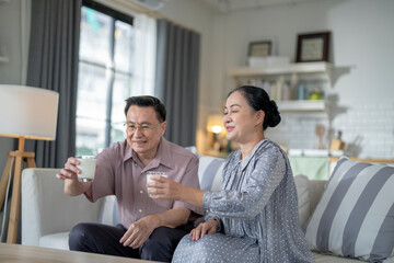 An elderly couple enjoys a peaceful moment at home, sharing smiles and drinks. The warm and cozy atmosphere emphasizes their deep connection, happiness, and the comfort of spending time together.