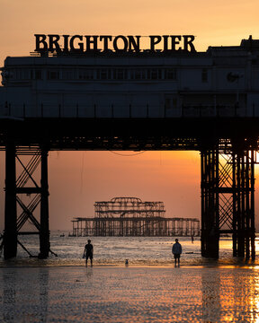 View of brighton pier at sunset with silhouettes of people, brighton, united kingdom.