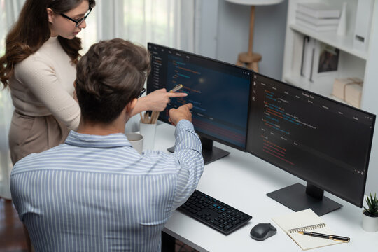 Team skilled developers program coding discussing creative website planning software project on two screen monitor's full stack data analyzing design at office with back side view concept. Postulate.