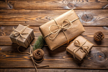 Rustic brown paper gifts tied with twine on wooden background with natural elements