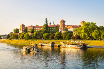 View of the historic katedra wawelska and serene river vistula with boats and trees, Krakow, Poland.