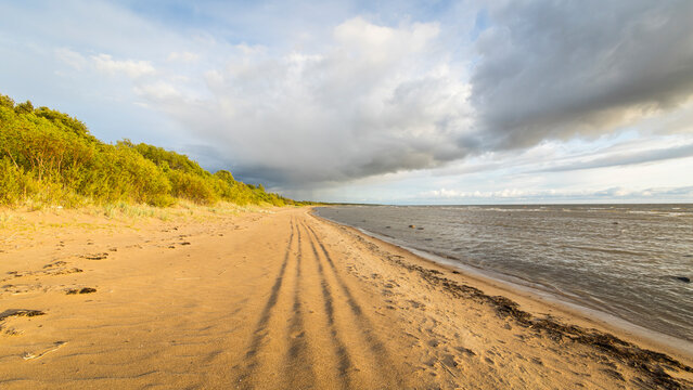 View of beautiful sandy beach and tranquil ocean under a serene sky with clouds, Paernu, Estonia.