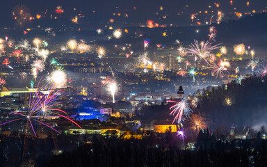 View of colorful fireworks over the vibrant city skyline with the clocktower and Schlossberg, Graz, Austria.