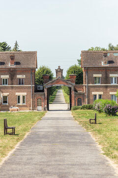 View of the serene Abbey of Our Lady of Dombes with beautiful brick buildings and a tranquil pathway, Le Plantay, France.