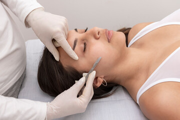 young woman on a table in a beauty center performing a beauty treatment for facial skin with a...