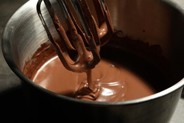 Chocolate dough dripping from mixer into bowl, closeup