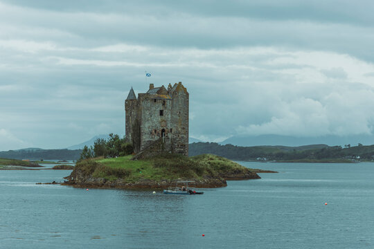 View of Castle Stalker on an island in Loch Linnhe with serene reflections and a picturesque sky, Appin, United Kingdom.