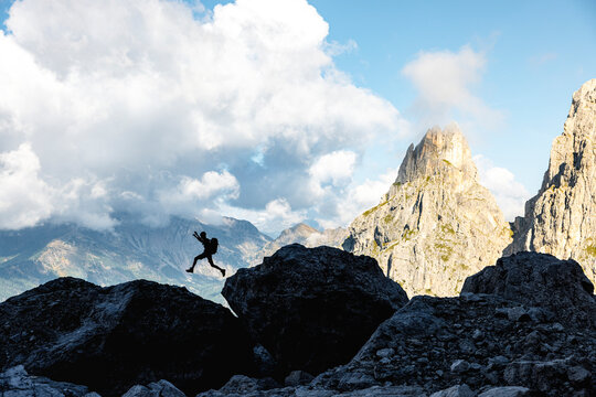 View of a Silhouette jumping rocks in front of The Dolomites in the Province of Trento, South Tirol, Italy