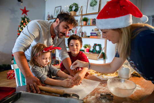 Family baking Christmas cookies together in festive kitchen