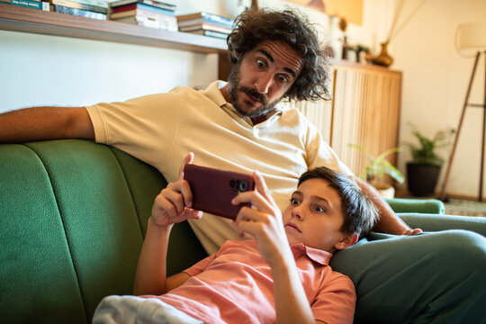 Father and son reacting to something surprising on a smartphone screen
