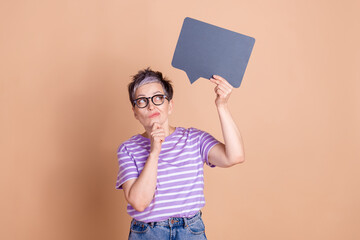 Photo of dreamy clever woman wear striped stylish clothes hand hold empty space isolated on beige color background