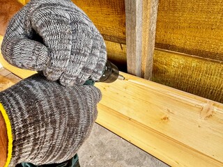 A man uses a screwdriver to nail a board during the construction of a gazebo.