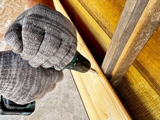 A man uses a screwdriver to nail a board during the construction of a gazebo.