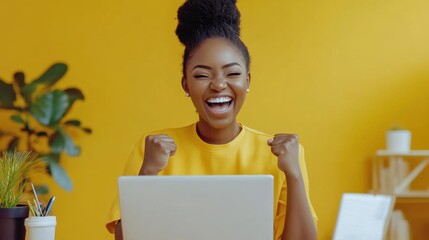 Young woman sitting at a desk with a laptop, smiling widely and clenching her fists in celebration of her success. Bright, inviting background that emphasizes her joy and accomplishment.