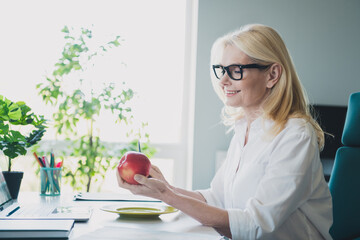 Photo of successful finance accountant manager blonde lady wearing formal white shirt and eyeglasses cutting apple having lunch
