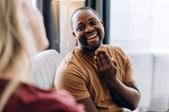 Happy African American man communicating with woman using sign language in cozy living room