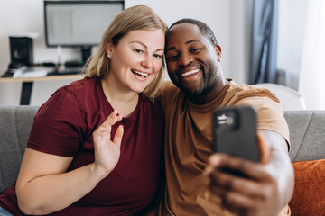 Happy loving couple making selfie on the mobile phone at home