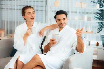 Beauty or body treatment spa salon vacation lifestyle concept with couple wearing bathrobe relaxing with drinks in luxurious hotel spa or resort room. Vacation and leisure relaxation. Quiescent